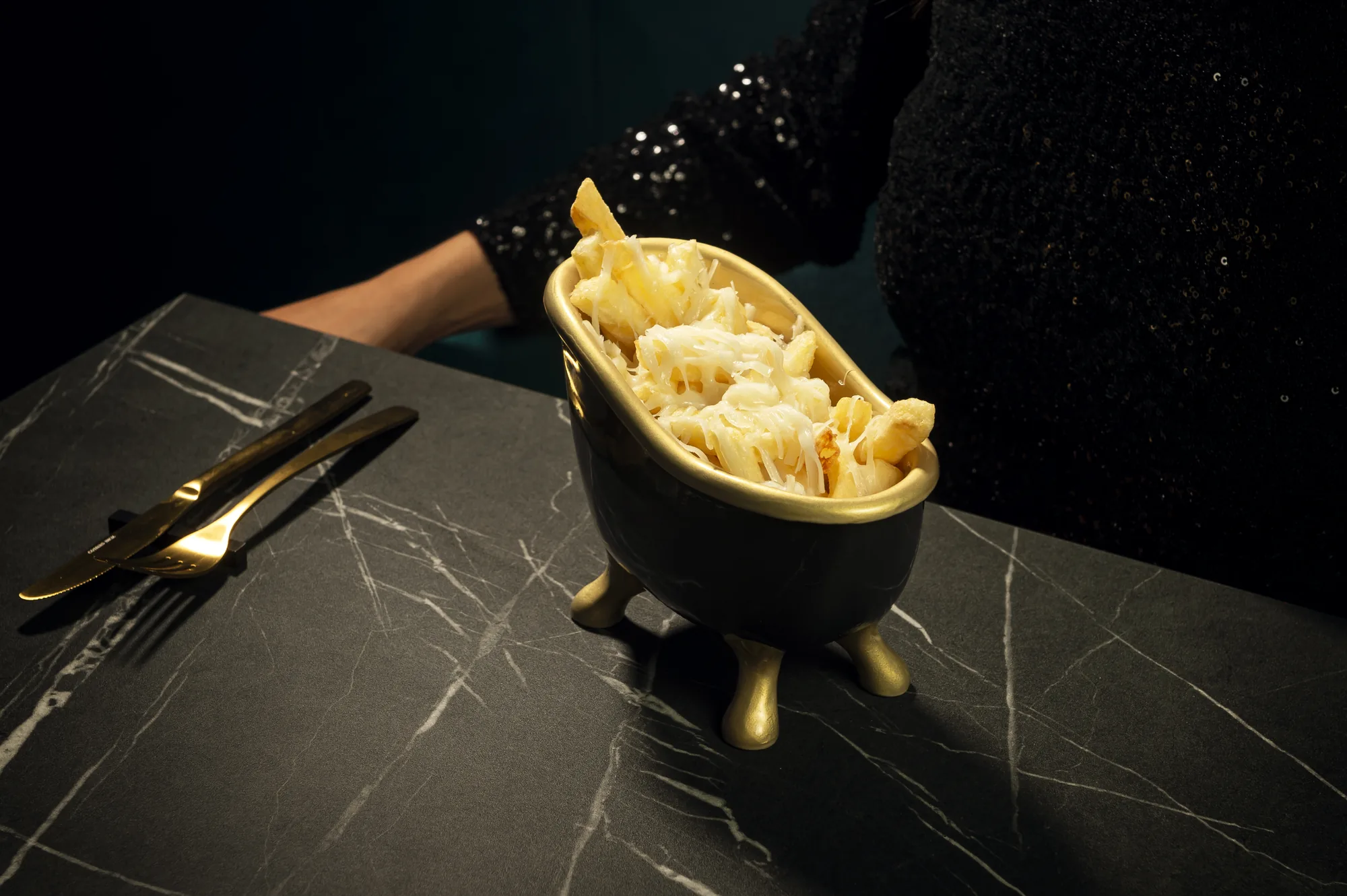 Patatas fritas con parmesano y trufa servidas en cazuela dorada, Oculto Nerja
